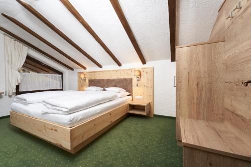 Schlafzimmer mit einem großen Bett mit einem Kopfteil aus Holz in der Unterkunft Hotel am Hof in Sölden
