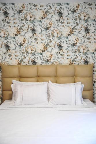 a bed with white pillows and a floral wallpaper at Apartman Ljubica in Vrnjačka Banja