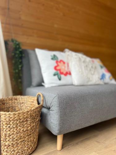 a gray couch with a pillow and a basket at Woodhide - Cottages near Batumi, Georgia in Zeda Ch'khutunet'i