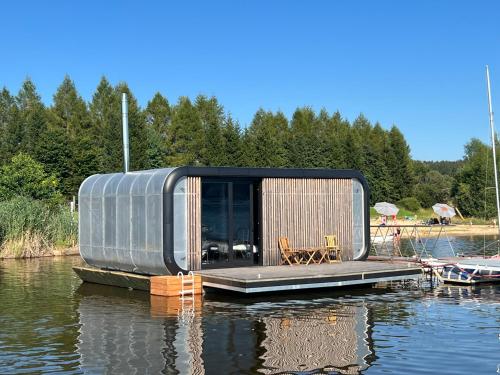 une petite maison sur un quai dans l'eau dans l'établissement Fontána Lipno, à Černá v Pošumaví