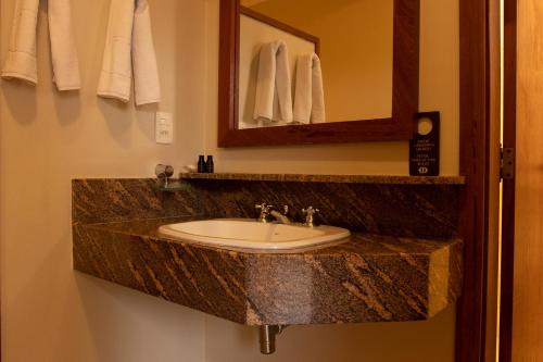 y baño con lavabo, espejo y toallas. en Hotel OT, en Três Lagoas