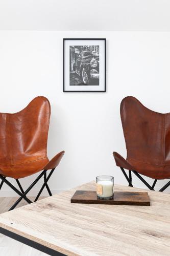 two leather chairs and a candle on a table at Le Beauvoir in Saint-Marcellin