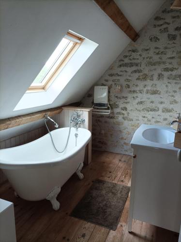 La salle de bains est pourvue d'une baignoire blanche et d'un lavabo. dans l'établissement Longère avec piscine, à Couffy