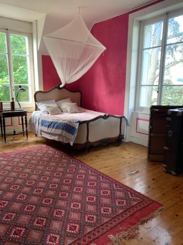 um quarto com uma cama e uma parede vermelha em Château de Monteux em La Fouillouse
