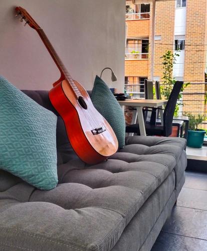 a guitar is hanging on a couch with pillows at Hostel Metro Floresta Alojamiento in Medellín
