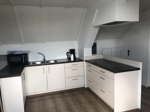 a kitchen with white cabinets and a sink at slapen bij alpacas in Beerse