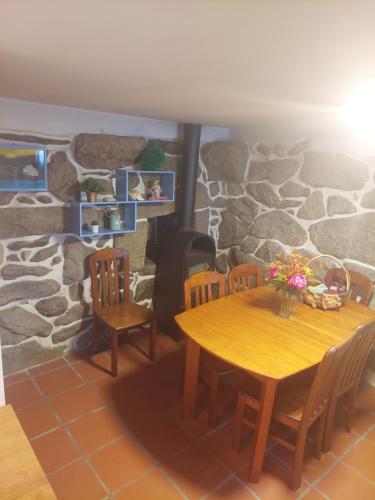 ein Esszimmer mit einem Tisch, Stühlen und einer Steinmauer in der Unterkunft Retiro do Mestre in Mondim de Basto