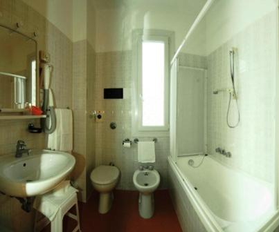 W łazience znajduje się umywalka, toaleta i wanna. w obiekcie Al Cavallino Bianco w Lignano Sabbiadoro