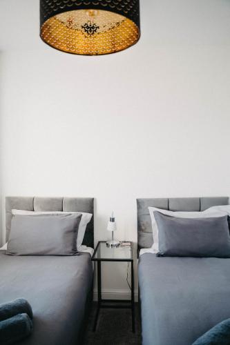 a bedroom with two beds and a table with a lamp at Flat Iron Anfield in Liverpool