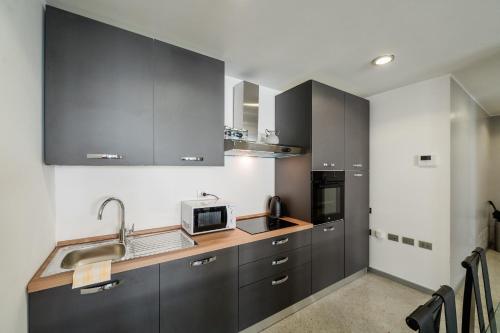 a kitchen with gray cabinets and a sink and a microwave at P&P Luxury Apartment in Bergamo