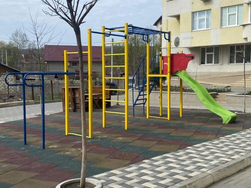 a playground with a green slide and a swing at Небольшая, мега уютная квартира in Chişinău