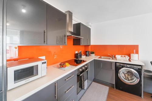 a kitchen with gray cabinets and an orange wall at 2 Bed In Southampton City With Free Parking in Southampton