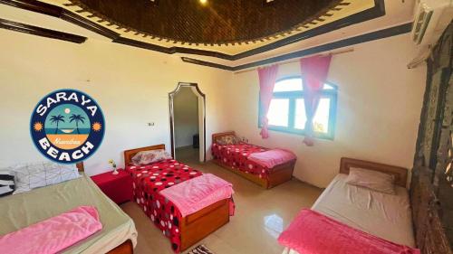 um quarto com três camas e uma placa na parede em New Saraya Camp em Nuweiba