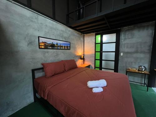 1 dormitorio con 1 cama roja y 2 toallas en เป่าฟู่เฮ้าส์ Bao Fu's House en Chumphon