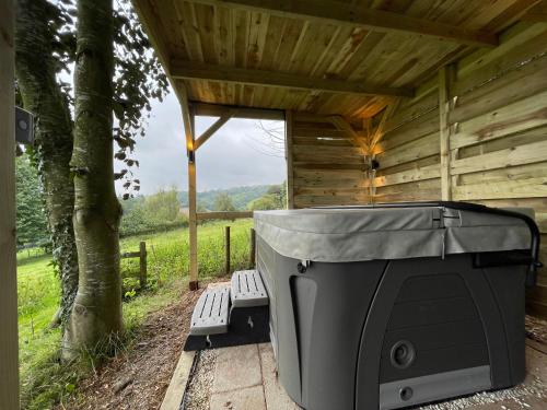 a screened in porch with a grill and two benches at Upper Gelli Luxury Holiday Lodge, Converted Dairy & Cosy Shepherds Huts in Welshpool
