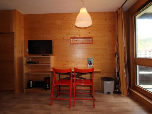 - une salle à manger avec deux chaises rouges et une table dans l'établissement Studio rénové proche pistes avec balcon - FR-1-502-386, à Tignes