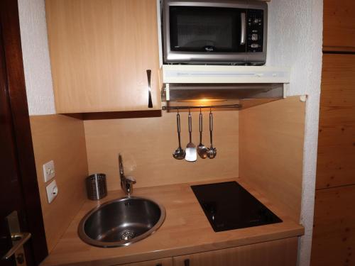 une petite cuisine avec un évier et un micro-ondes dans l'établissement Studio rénové proche pistes avec balcon - FR-1-502-386, à Tignes