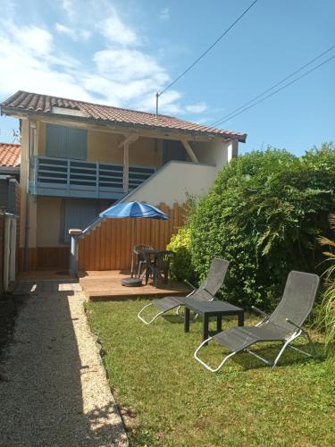 Grièges的住宿－Appartement a la campagne，庭院配有两把椅子和一张桌子以及一把雨伞