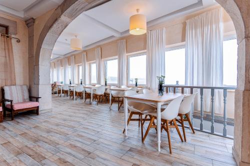 uma sala de jantar com mesas, cadeiras e janelas em Residencial Real Guest House em Sintra