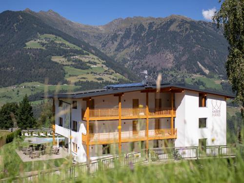 a house on a hill with mountains in the background at Natur Residence Kaiser Hans in Schenna