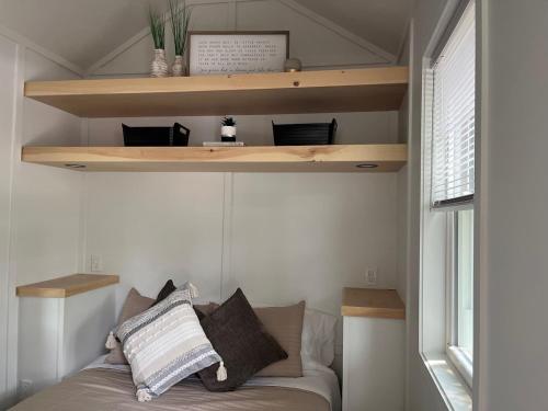 - une chambre avec des étagères en bois et un lit avec des oreillers dans l'établissement The Tiny Getaway Home, à Elizabethtown