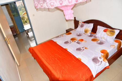 sypialnia z łóżkiem z pomarańczową pościelą i poduszkami w obiekcie Enchante Suites Kigali w mieście Kigali