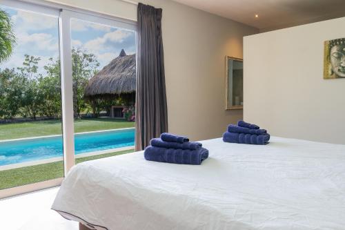 Un dormitorio con una cama con toallas azules. en Stylish 4 Bedroom Modern Villa Design, Walking Distance From The Beach, en Jan Thiel
