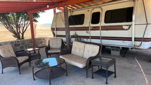 a group of chairs and tables on a porch with an rv at Rancho Matalote en Valle de Guadalupe in Valle de Guadalupe