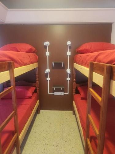 a bedroom with two bunk beds with red sheets at Pachá Hostel Backpack in Salta