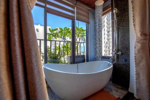 uma banheira na casa de banho com uma grande janela em Taian Hotel & Apartment em Da Nang