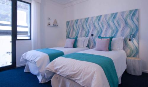 two beds in a hotel room with white and blue at Mediterrâneo Madeira in São Vicente