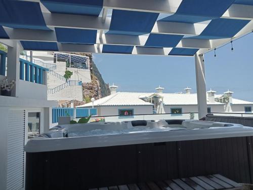 a hot tub on a balcony with a blue and white roof at Mediterrâneo Madeira in São Vicente