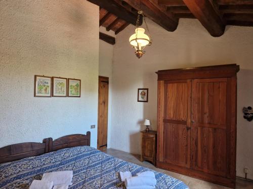 a bedroom with a bed and a wooden cabinet at ABBAZIA DI VALLINGEGNO in Gubbio