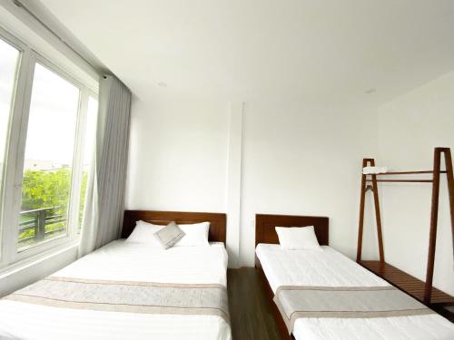 dwa łóżka w pokoju z oknem w obiekcie Hideaway Homestay w mieście Phong Nha
