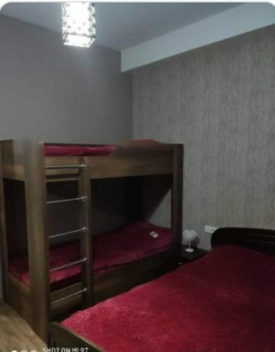 a bedroom with two bunk beds with red sheets at Didveli residenc in Bakuriani