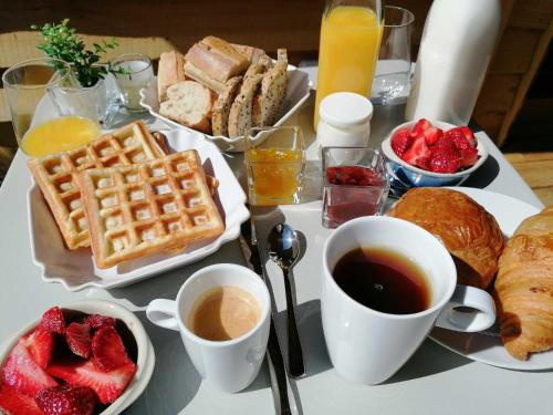 a table topped with breakfast foods and coffee and fruit at Les Cabanes Suspendues in Satillieu