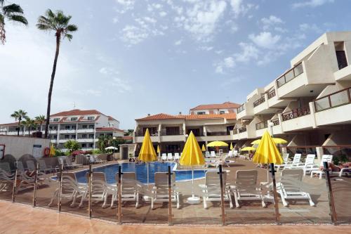 a swimming pool with chairs and umbrellas in a resort at Hotel-Apartamentos Andorra in Playa de las Americas