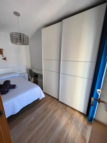 - une chambre avec un lit blanc et une porte coulissante dans l'établissement Bonito apartamento en Granada (zona palacio congresos y metro), à Grenade