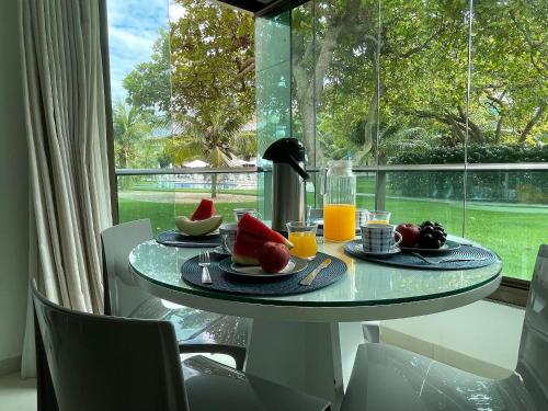 una mesa con comida y fruta delante de una ventana en Carneiros Beach Resort Flat Térreo 2 quartos en Praia dos Carneiros