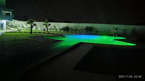 a swimming pool lit up at night with green lights at Chambres d'hôtes - Écohâme - Guitar Palace in Ouazzane