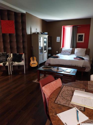 una camera con un letto, un tavolo e una chitarra di Gite de la Piegerie a Courgenard