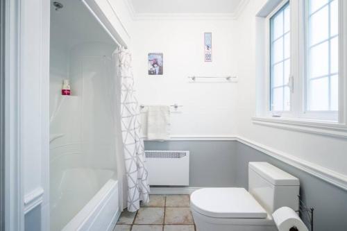 La salle de bains blanche est pourvue d'une douche et de toilettes. dans l'établissement Le rocher - St-Adolphe, à Saint-Adolphe-d'Howard