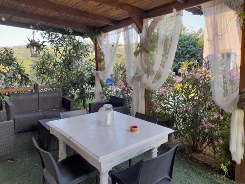 a white table and chairs under a pergola at Madama Langa Country House con piscina nelle vigne in Montelupo Albese
