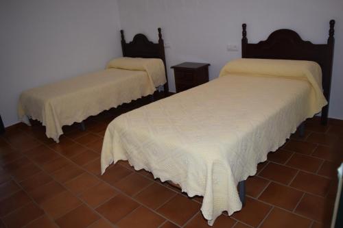 a room with two beds with white sheets on them at Casa Rural Los Pinos in Hinojos