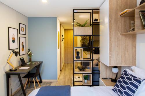 a bedroom with a bed and a desk and a room with a deskablish at NUEVO! Apartamento zona T 85 Bogota in Bogotá