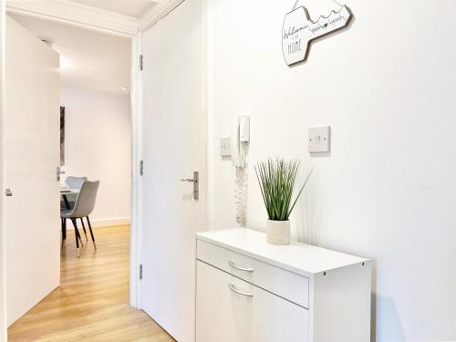 a white kitchen with a cabinet and a clock on the wall at 2 Modern Double Bed Apartment for 6 Guests By Hofin Stays Short Lets & Serviced Accommodation in London