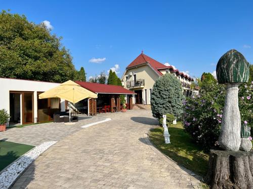 a patio with an umbrella and a building at Bajor Panzió Bük-Bükfürdő, Adults Friendly 12 Plus in Bük