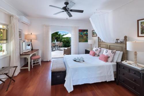 Un dormitorio con una cama, un escritorio y un ventilador de techo. en Hectors House Blue Sky Luxury, en Christ Church