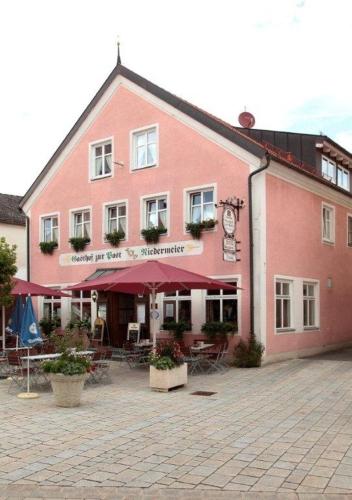 een rood gebouw met tafels en stoelen ervoor bij Hotel zur Post Garni in Dietfurt