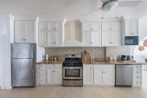 a kitchen with white cabinets and a stainless steel refrigerator at Exceptional Beachfront Living - Milord Sunsets home in Saint James